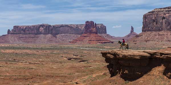 Farbfoto für die-besten-spielfilme: ein einsamer Cowboys auf seinem Pferd in den riesigen Weiten des Monument Valley, Arizona.