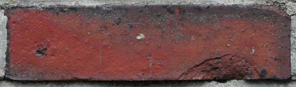 Rostroter Ziegelstein in einem Mauerwerk.